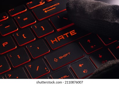 Close-up laptop keyboard with Red  light button Hate. Finger in glove - Shutterstock ID 2110876007
