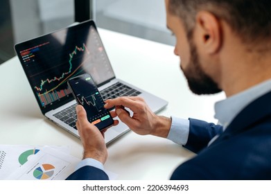 Close-up of laptop and smart phone screen with stock diagrams.Caucasian crypto trader investor using cellphone and laptop for cryptocurrency financial market analysis, buying or selling cryptocurrency - Shutterstock ID 2206394693