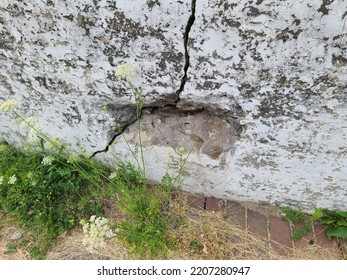 A Closeup Of A Large Concrete Slab With A Big Crack In It.