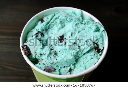 Closeup a Large Cup pf Mint Chocolate Chip Ice Cream on Dark Brown Wooden Table