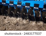 Close-up of a large modern plow blue color or disc harrow for cultivating the land. New model of agricultural equipment. 