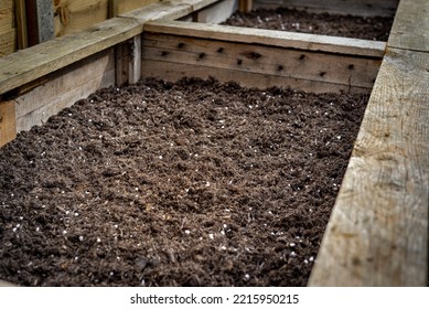 Closeup Of Large Wooden Home Made Planter Vegetable Box Container In Backyard Garden Filled With Organic Fertile Soil Ready For Planting Vegetable Seeds.