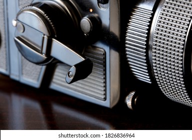 close-up, large-format camera (focus on film pass crank), on brown table