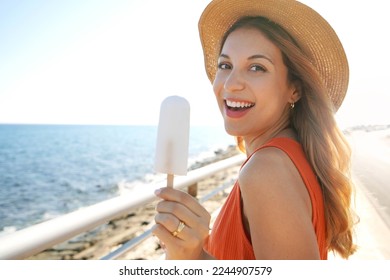 Close-up of laughing Brazilian woman eating a lemon popsicle looking at the camera on summer