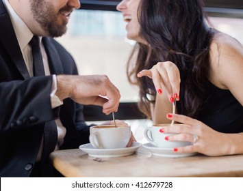 Closeup laughing young couple stirring coffee at coffee shop dressed in black