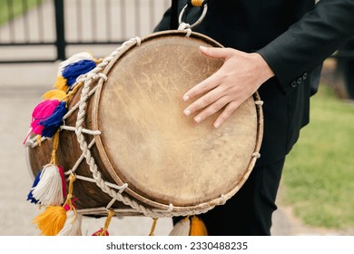 Close-up of a leather drum on a musician's neck. A street musician with a musical instrument in the form of a drum plays a rhythm. Festive musical accompaniment in the form of musical rhythm - Powered by Shutterstock