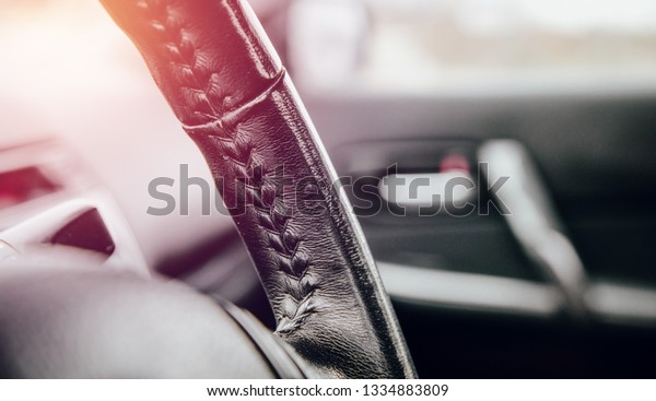 Close-up of the leather\
steering wheel in the car. Concept of car care, comfort in driving\
a car. Making changes in the car, wrapping the steering wheel in\
leather.