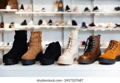 Closeup of leather and suede womens ankle boots displayed on shelves in shoe boutique.