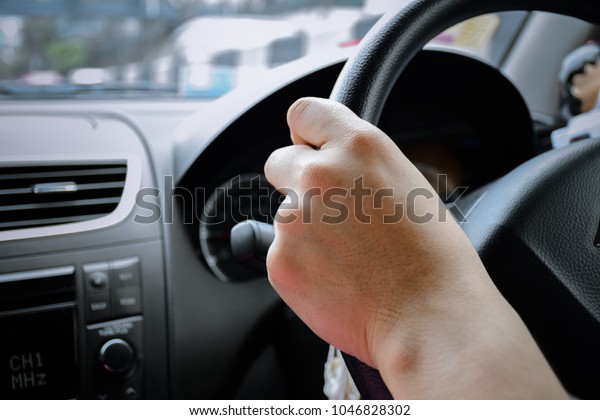 Closeup The left hand is holding part of
joystick of car and blur street or road view or left hand of man is
driving car and blur black console background or back hand male or
clutch or stranglehold
