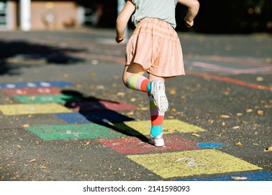 Closeup of leggs of little toddler girl playing hopscotch game drawn with colorful chalks on asphalt. Little active child jumping on playground outdoors on a sunny day. Summer activities for children. - Powered by Shutterstock