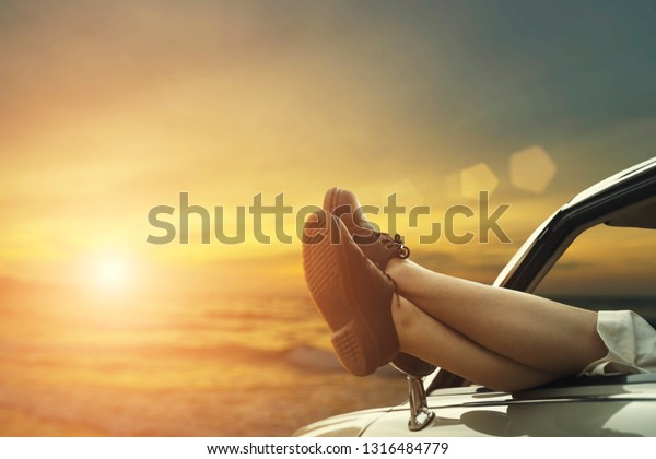 Closeup of legs in car with sunset. Freedom and\
travel concept.