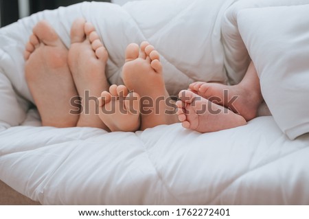 Close-up of the legs of the family of mom, daughter and little newborn son, covered with a plaid. Sleeping family. Time to sleep. 