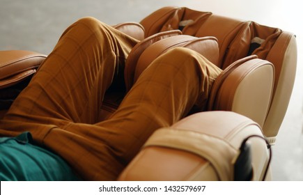  Closeup of legs of a man relaxing on the electric massage chair                                       