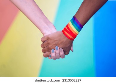 Close-up lesbian couple holding hands with rainbow background. LGBTI concept. - Powered by Shutterstock