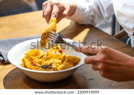 Close-up lifestyle girl in restaurant eat conchiglioni, conchigliette pasta with meat or green vegan meat, with vegetables, on terrace, hands in picture. Healthy italian, Mediterranean lunch