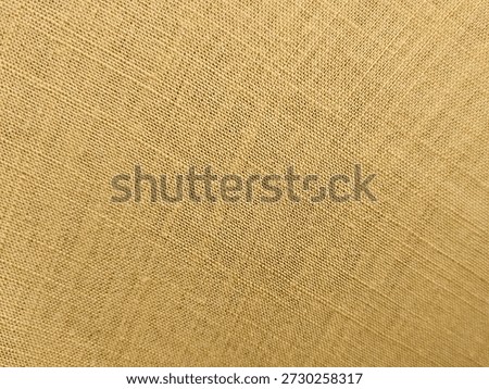 A close-up of light yellow woven burlap fabric showing textured threads and open weave structure.