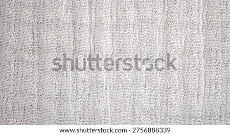 Close-up of a light-colored fabric surface featuring a subtle woven pattern with fine texture and soft neutral tones.