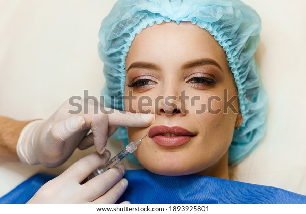 Closeup lips\
augmentation injections for attractive girl. Plastic surgeon does\
injection in lip in medical clinic. Cosmetic rejuvenating facial\
treatment. Empty space for\
advert