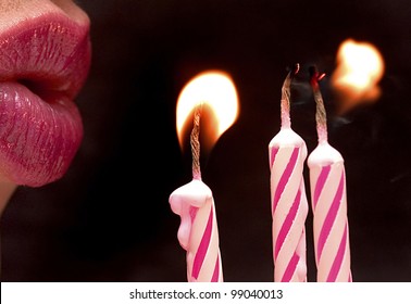 Close-up Of Lips Blowing Out Pink Candles