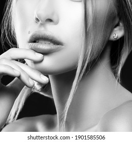 Close-up Lips, hand and part of face of beauty model woman. Natural nude make-up, clean skin. Black background. Skincare facial treatment concept. Monochrome
