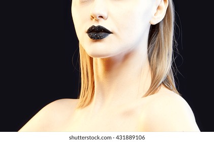 Close-up lips and shoulders of female caucasian young blonde model with black lipstick, fingernails. Studio portrait. Toned
