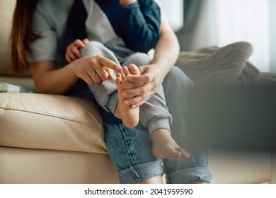 Close-up Of Little Boy Sitting On Mother's Lap While She's Touching His Toes. 