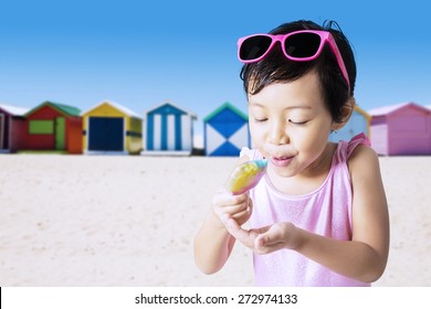 Closeup of little child eats a melt ice cream on the shore while wearing swimwear - Powered by Shutterstock