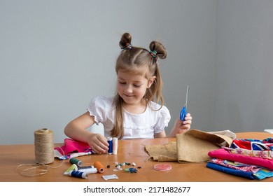 Close-up Of A Little Girl Sewing Things By Herself. Creates A Product With His Own Hands. The Child Is Learning To Sew. Sustainable Development Of The Life Of A Child And An Adult. Conscious And Reusa