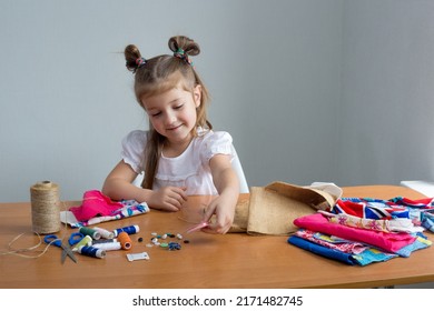 Close-up Of A Little Girl Sewing Things By Herself. Creates A Product With His Own Hands. The Child Is Learning To Sew. Sustainable Development Of The Life Of A Child And An Adult. Conscious And Reusa