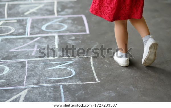 Closeup of little girl's
legs and hop scotch drawn on asphalt. Child playing hopscotch game
on playground outdoors on a sunny day. Summer activities for
children.