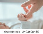 Close-up little hand of child baby holding hand of mother, A newborn holds on to mom