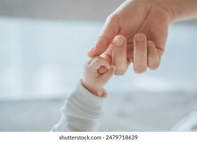 Close-up little hand of child baby holding hand of mother, A newborn holds on to mom's, dad's finger, Love and relationship with infant, Care and support, Dreaming and protection - Powered by Shutterstock