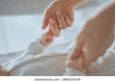 Close-up little hand of child baby holding hand of mother, A newborn holds on to mom's, dad's finger, Love and relationship with infant, Care and support, Dreaming and protection - Powered by Shutterstock