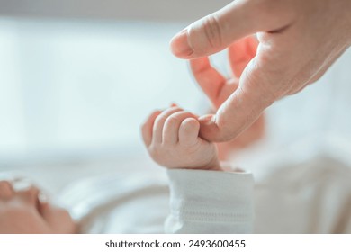 Close-up little hand of child baby holding hand of mother, A newborn holds on to mom's, dad's finger, Love and relationship with infant, Care and support, Dreaming and protection