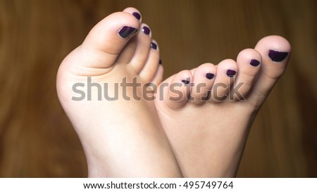 closeup of a little toddler girl isolated foot and nails vanish and wooden background