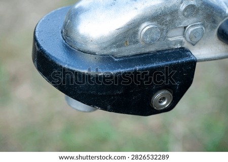 Close-up of a locking device fitted to a metal trailer hitch coupler. Detailed view of a used trailer coupling lock designed to secure the towing connection against unauthorized use.