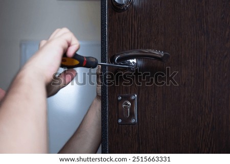 Close-up of a locksmith using a screwdriver to secure a door lock, home entry security and safety