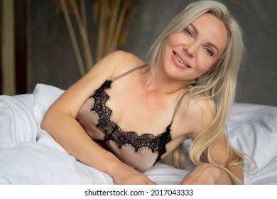 Close-up Of A Lovely Sexy Blonde Girl In A Nightie Lying On The Bed At Home On White Bedding. Morning Of The Bride. Good Morning Women Weekend. Women's Health Concept. High Quality Photo