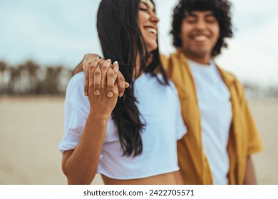 Closeup of loving couple holding hands while walking at sunset.  Shot of an couple holding hands while at the beach. Young romantic hipster couple on summer island holidays holding hands  - Powered by Shutterstock