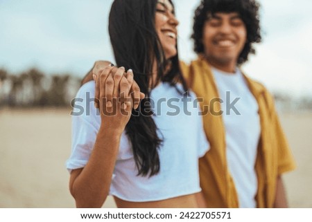 Closeup of loving couple holding hands while walking at sunset.  Shot of an couple holding hands while at the beach. Young romantic hipster couple on summer island holidays holding hands 