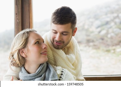 Close-up Of A Loving Young Couple In Winter Clothing Against Cabin Window