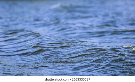 A close-up low angle dynamic shot of small waves rippling on the ocean surface.