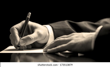 Closeup low angle perspective of a businessman in a suit signing a document with a fountain pen as he closes a business deal or finalises a contract or agreement