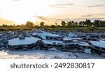 Close-up low angle view of a pile of rubble of a brick wall on the ground that was demolished from an old building with the early morning sun rising in the background in the Thai countryside.