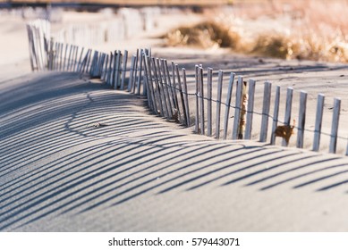 Closeup Low Angle View Of Weathered Wood Slat Fence Along Beach In Late Afternoon Sun