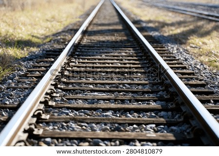A close-up, low-angle shot of parallel railroad tracks disappearing into the horizon, emphasizing depth and perspective.