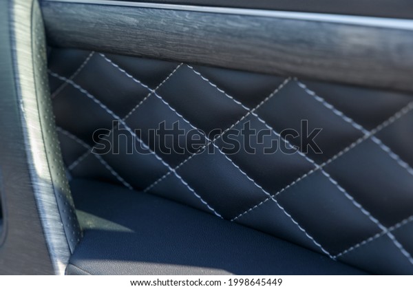 Close-up\
luxury leather interior trim with white diamond stitching. Door\
trim stitching. Car interior. Luxurious car instrument cluster.\
Close up shot of automobile instrument\
panel