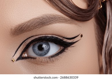 Close-up macro of a blue eye with dramatic black winged eyeliner and precise graphic lines, sharp studio lighting emphasizing lash with eye liner, pigment and editorial beauty makeup