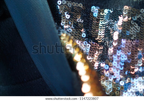 Closeup macro of clothe with black\
whool fabric, pink and yellow bright strasses, plus car dark\
security belt detail, making abstract texture and\
pattern.