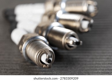Close-up macro image of multiple spark plugs on textured dark surface, vital components of gasoline engine ignition system for vehicle performance